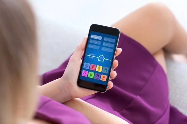 Woman in purple dress holding phone with app smart home — Stock Photo, Image