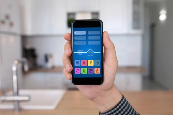 Manlig hand håller telefonen med appen smart hem kök hus — Stockfoto