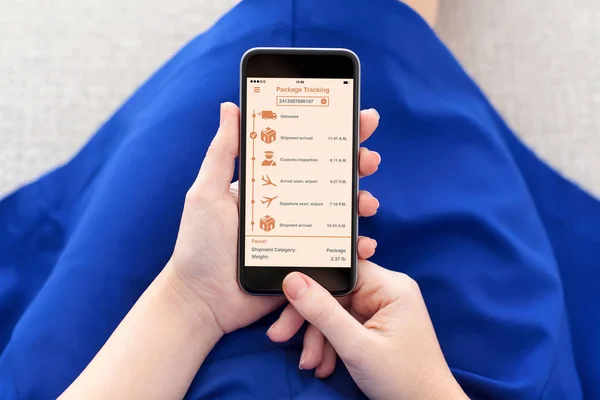 Женщина держит телефон с приложением отслеживания доставки пакета на экране — стоковое фото
