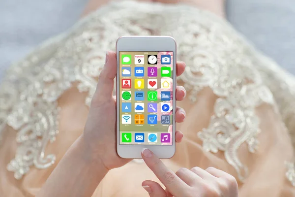 Žena zlaté šaty drží telefon s domovskou obrazovku ikony aplikace — Stock fotografie