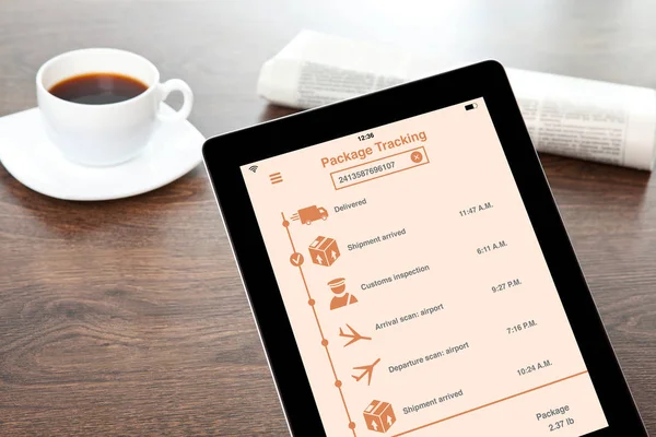 Computer tablet with app tracking delivery package on table — Stock Photo, Image