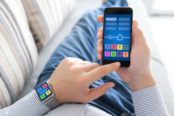 Mann hält Uhr und Handy mit Smart-Home-Bildschirm — Stockfoto