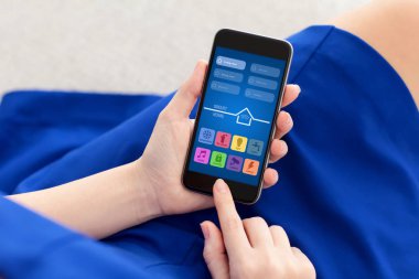 telefon ile app akıllı ev tutarak mavi elbiseli kadın