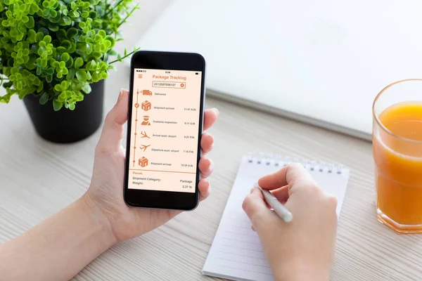 Kvinnor hand håller telefonen med app spåra leveransen paket — Stockfoto