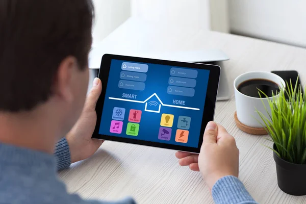 Hombre sentado en la habitación y la celebración de la tableta con aplicación inteligente — Foto de Stock