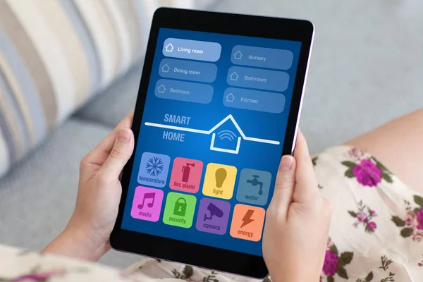 Frau im geblümten Kleid hält Tablet mit App Smart Home in der Hand — Stockfoto