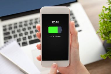 ekranda beyaz telefon şarj edilmiş bir batarya ile tutarak el