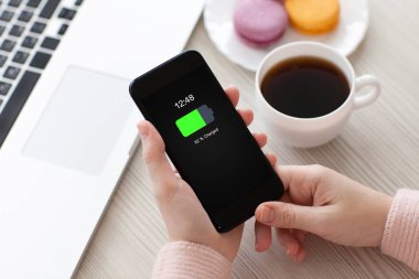 Telefon şarj edilmiş bir batarya ekran ile masaya holding kadınlar eller