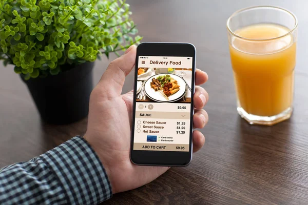 Мужчина держит в руке телефон с приложением доставки еды на экране — стоковое фото