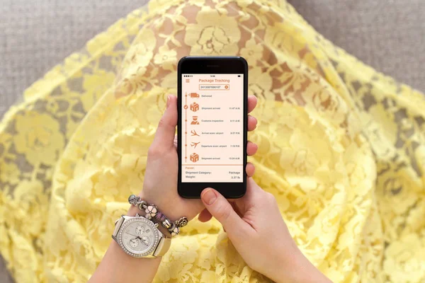 Woman yellow dress holding phone app tracking delivery package — Stock Photo, Image