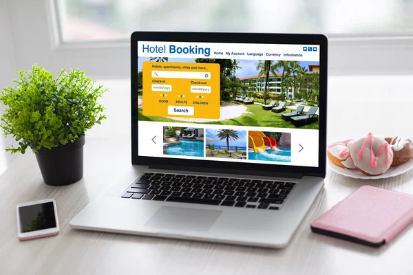 Laptop with online search booking hotel on screen and phone — Stock Photo, Image