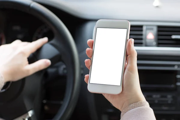 Kobiece ręce trzymając telefon z ekranem na białym tle za kierownicą samochodu — Zdjęcie stockowe