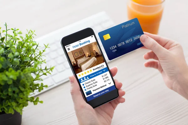 Weibliche Hände halten Telefon-App Hotelbuchung und Kreditkarte — Stockfoto