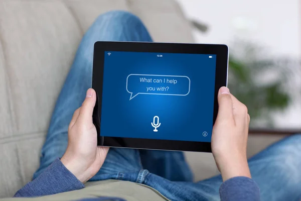 Uomo sul divano con tablet con app schermo assistente personale — Foto Stock