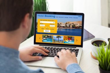dizüstü bilgisayar ekranında otel rezervasyonu ile birlikte oturan adam 