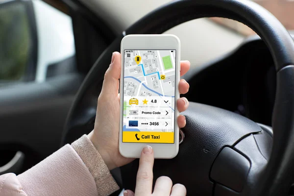 Handen van de vrouw met telefoon met app taxi bellen in de auto — Stockfoto