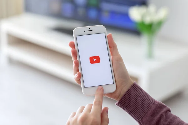 Woman holding iPhone with video service YouTube on screen — Stock Photo, Image