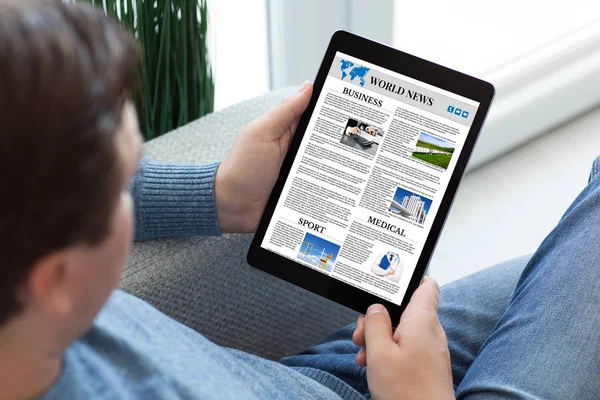 Man in jeans holding tablet computer with app world news — Stock Photo, Image