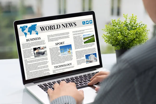 Мужчина держит в руках компьютер с экраном мировых новостей — стоковое фото