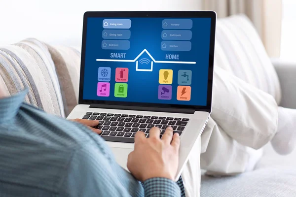 Человек в комнате держит ноутбук с приложением умный дом — стоковое фото
