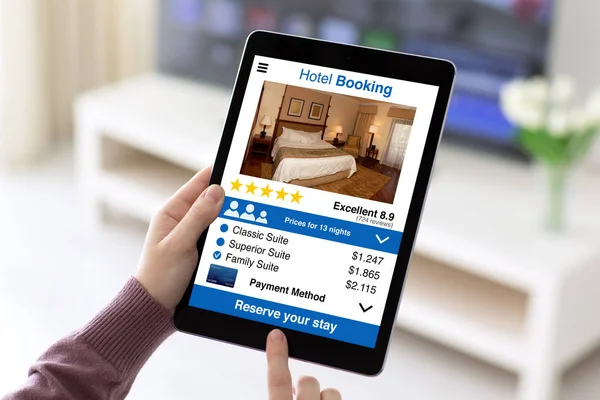 Manos femeninas sosteniendo la tableta con la aplicación de reserva de hotel en pantalla —  Fotos de Stock