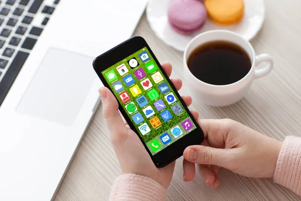 Handen van de vrouw met telefoon met beginscherm pictogrammen apps notebook — Stockfoto