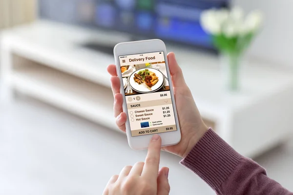 Vrouwelijke handen met telefoon met app levering voedsel op scherm — Stockfoto