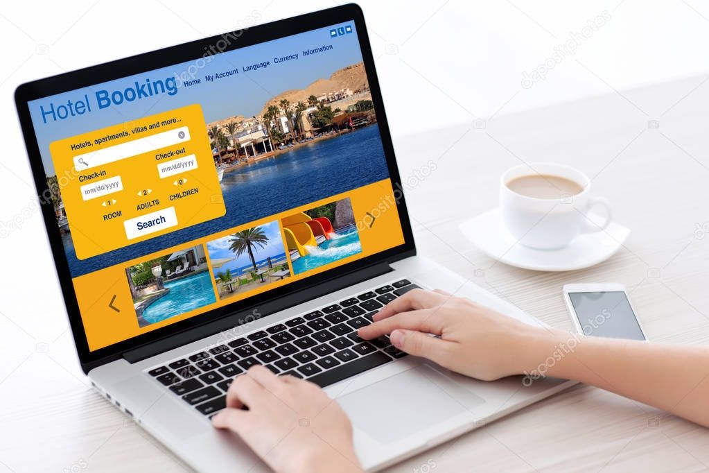 woman hands typing on laptop keyboard with hotel booking screen
