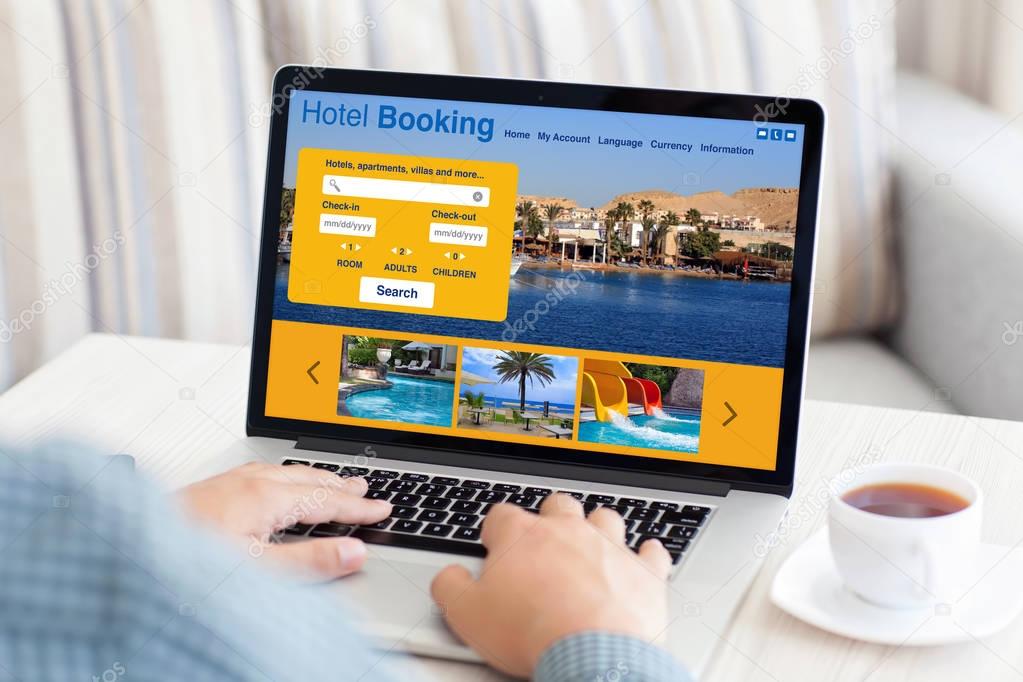 man typing on laptop keyboard with hotel booking screen room