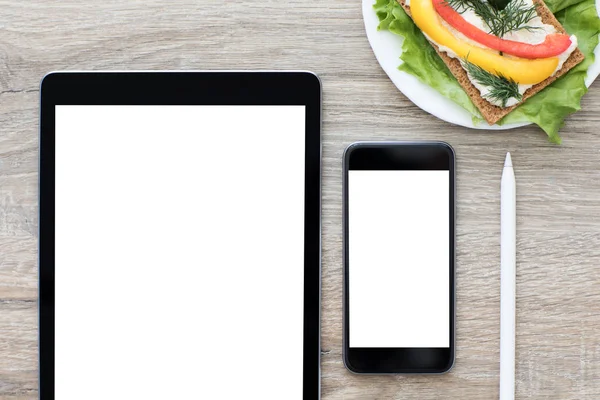 Computer tablet and phone with isolated screen on the table — Stock Photo, Image