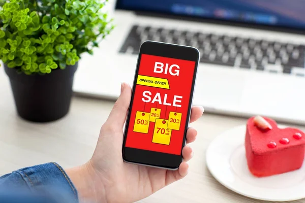 Hand van de vrouwen met telefoon met grote verkoop scherm op tafel — Stockfoto