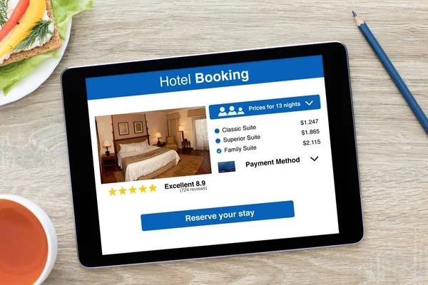 Tableta de ordenador con aplicación reserva de hotel en pantalla mesa de madera — Foto de Stock