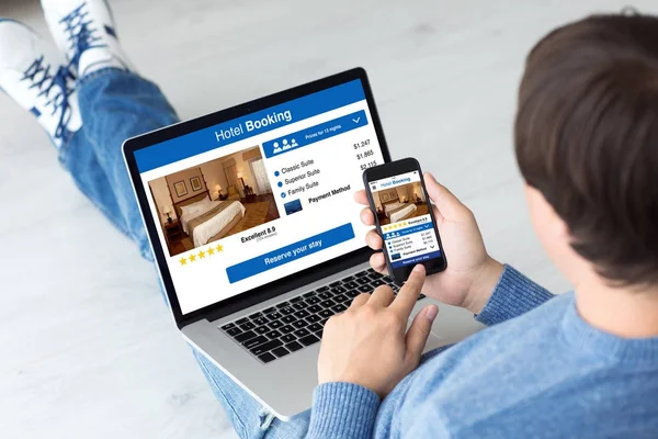 Man holding computer and phone with app hotel booking — Stock Photo, Image