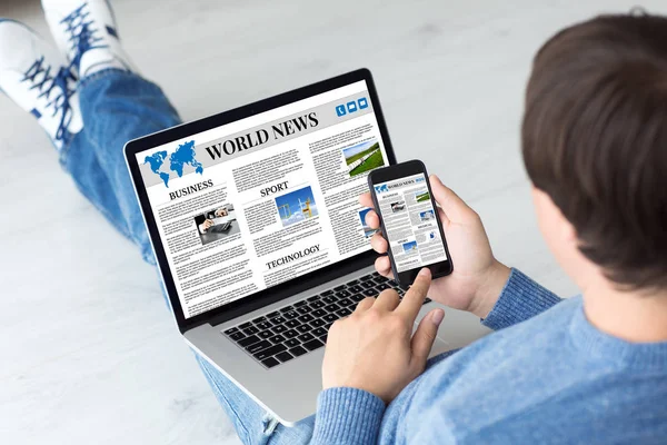 Man holding computer and phone with app world news — Stock Photo, Image