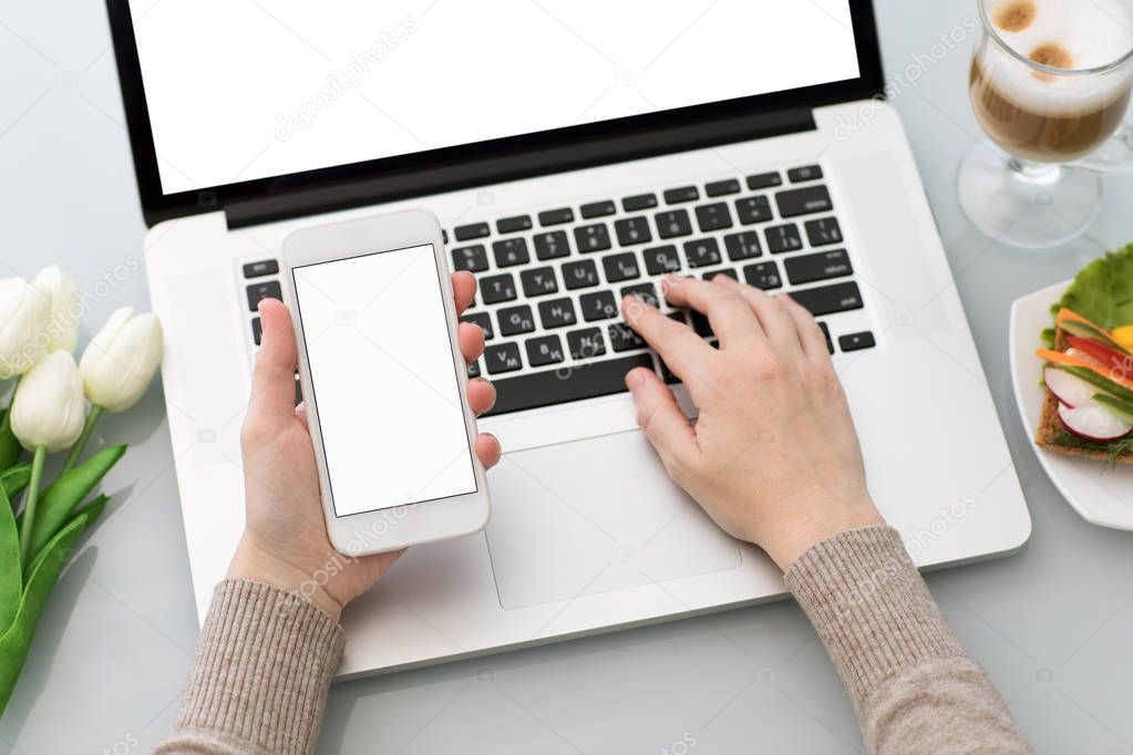 female hands typing laptop keyboard and holding phone with isola