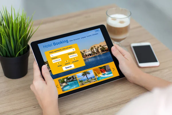 Kvinna som håller tablett dator med appen hotellbokning på skärmen — Stockfoto
