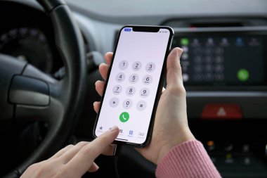 Kadın el iPhone X yer numarası ile arabanın içinde tutarak