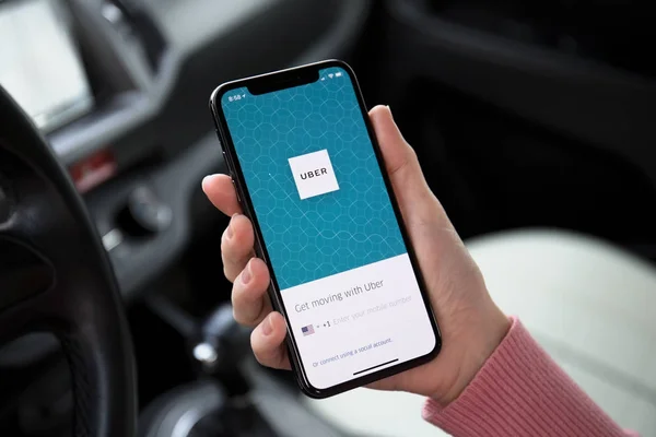 Mulher mão segurando iPhone X com aplicação Táxi Uber — Fotografia de Stock