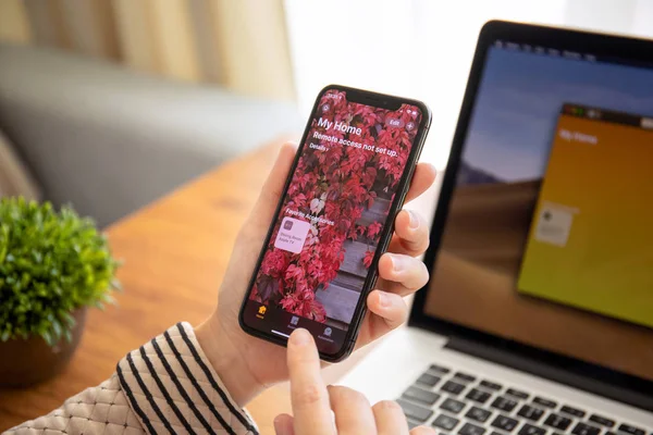 Mulher mão segurando iPhone X com aplicativo Home na tela — Fotografia de Stock