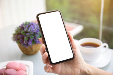 Kafede izole edilmiş ekranı olan telefonu tutan kadın elleri