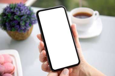 Kafede izole edilmiş ekranı olan telefonu tutan kadın elleri