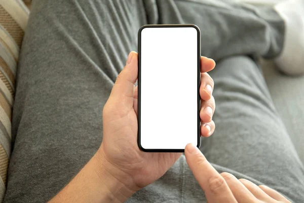 Male hands holding phone with isolated screen on sofa — Stock Photo, Image