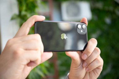 iPhone 11 'i tutan adam fotoğraf makineli telefon çekiyor.