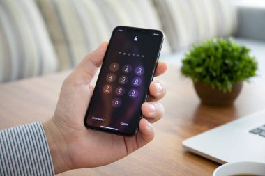 Ekranda Pin kodu olan iPhone X 'i tutan adam