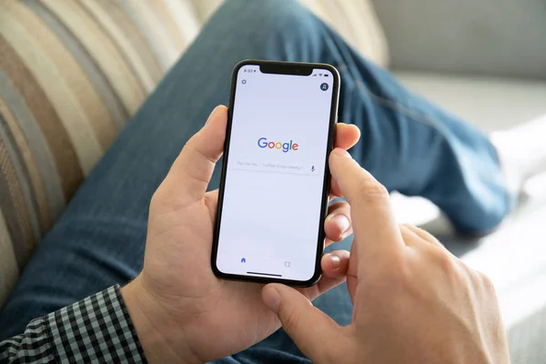 Мужчина держит iPhone X с сервисом социальной сети Google — стоковое фото