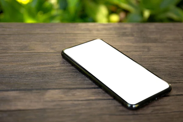 Telefoon met geïsoleerd scherm op een tafel achtergrond van de natuur — Stockfoto