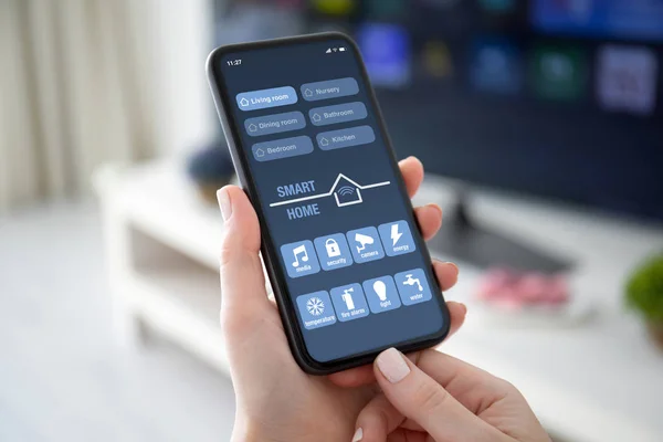 Женские руки держат телефон с приложением умный дом на экране — стоковое фото