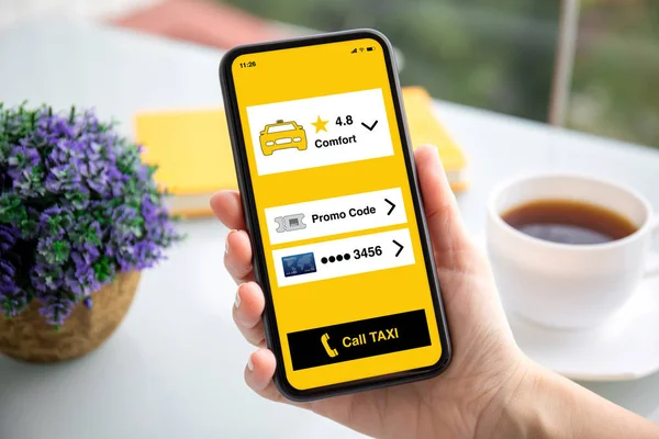 Женская рука держит телефон с приложением вызова такси на экране — стоковое фото