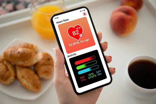 Kobieta ręka trzyma telefon z aplikacji serca i aktywności — Zdjęcie stockowe