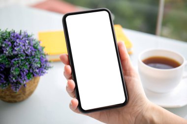 Kadın eli telefonu kafede yalnız bir ekranda tutuyor.